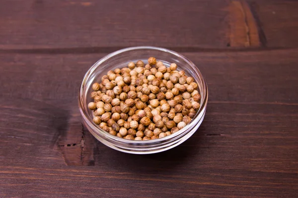 Coriander seeds on bowl over wood — Stock Photo, Image