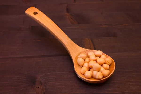 Garbanzos cocidos en una cuchara de madera sobre madera — Foto de Stock