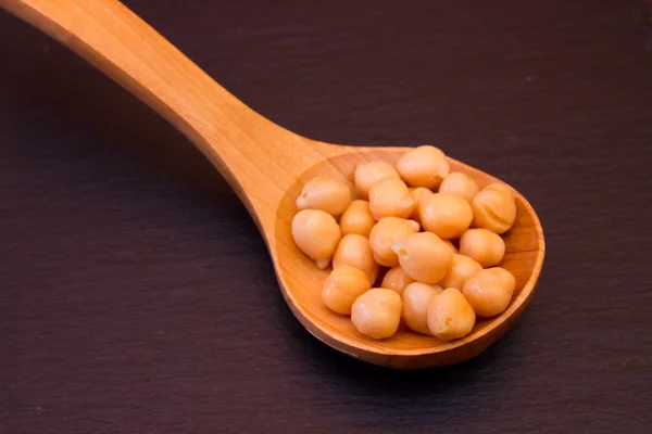 Boiled chickpeas on a wooden spoon on slate Stock Photo