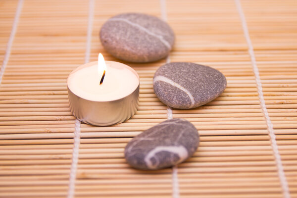 Stones and a candle on a bamboo mat
