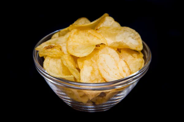 Bowl with potato chips on black — Stock Photo, Image