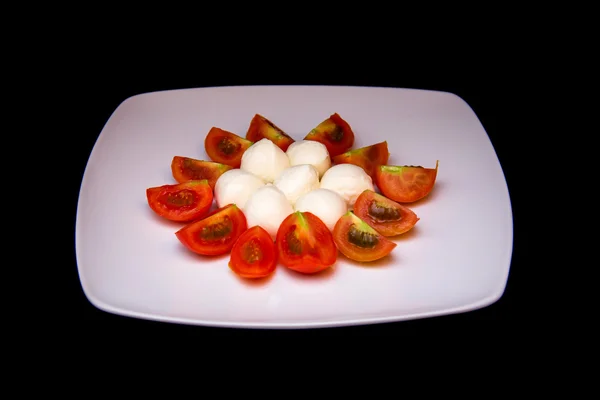 Placa con mozzarella y tomate sobre negro — Foto de Stock