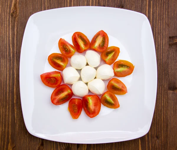 Plate with mozzarella and tomato on wood from above — Stock Photo, Image