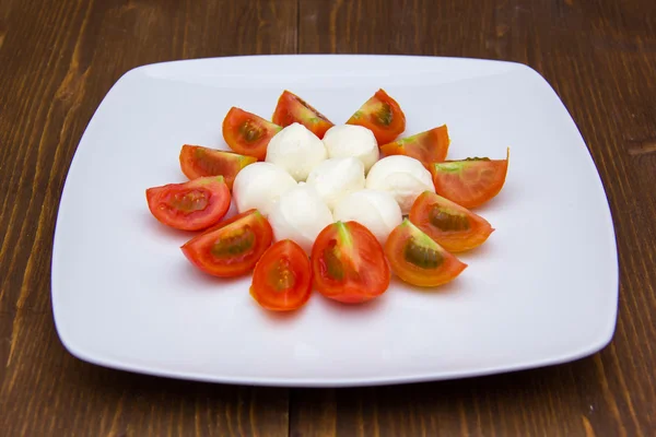 Plate with mozzarella and tomato on wood — Stock Photo, Image