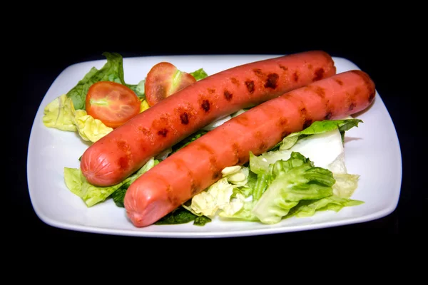 Sausages with salad on black — Stock Photo, Image