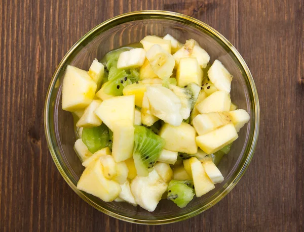 Bowl with fruit salad on wood from above — Stock Photo, Image