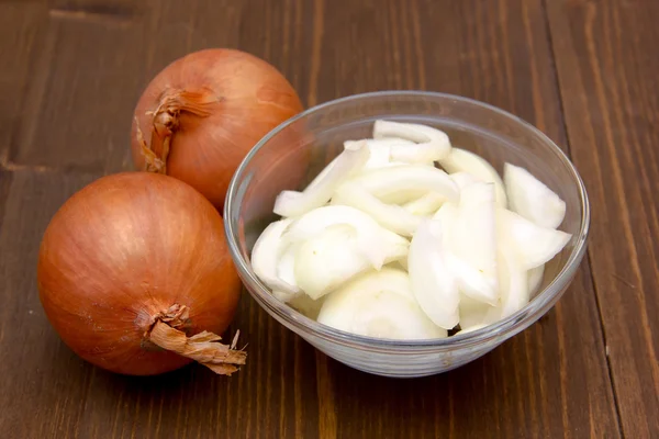 Schüssel mit geschnittenen Zwiebeln auf Holz — Stockfoto