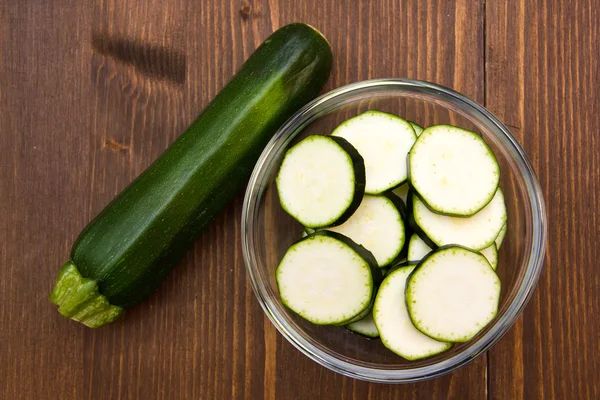 Schüssel mit Zucchini-Scheiben auf Holz von oben — Stockfoto