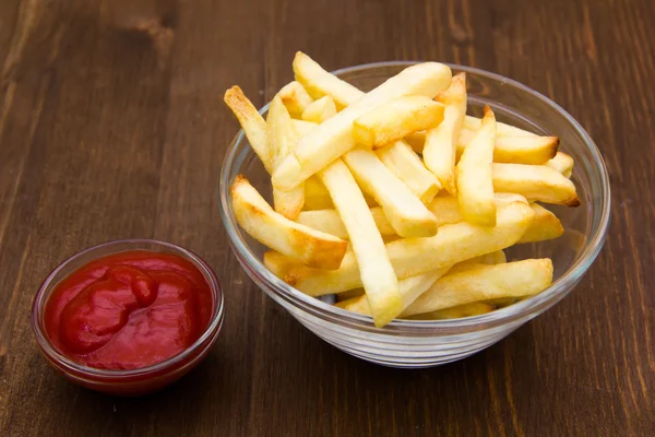 Tigela de batatas fritas e ketchup em madeira — Fotografia de Stock