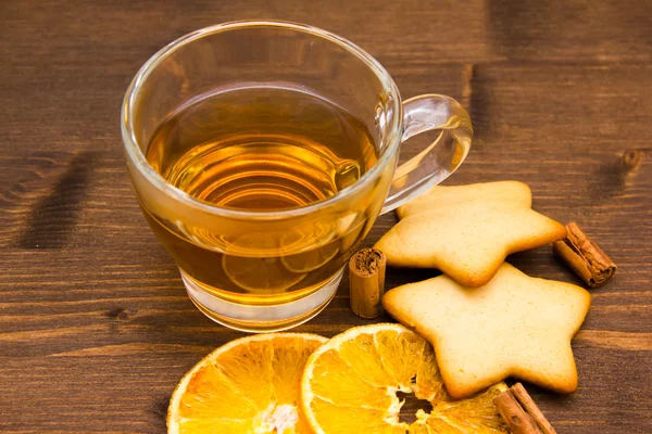 Чай и печенье с апельсином и корицей на дереве рядом — стоковое фото