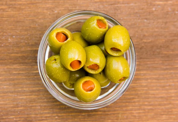 Stuffed olives in bowl on wood from above — Stock Photo, Image