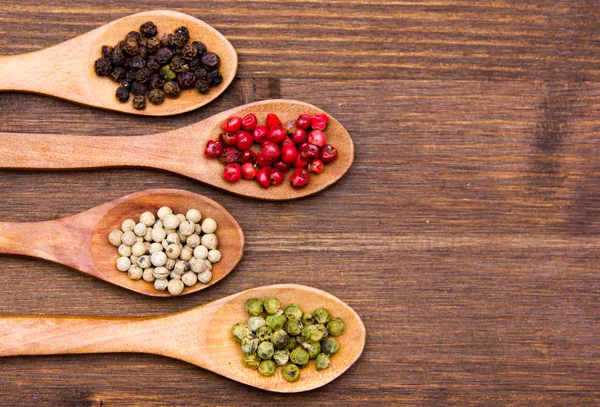 Träskedar med paprika blandat en hand på trä — Stockfoto