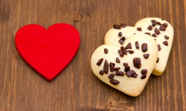 Biscuits et petit coeur rouge sur bois — Photo