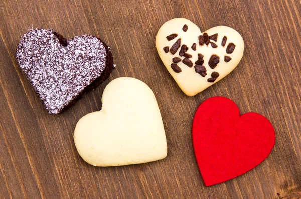 Cakes and cookies in the shape of heart on wood from above — Stock Photo, Image