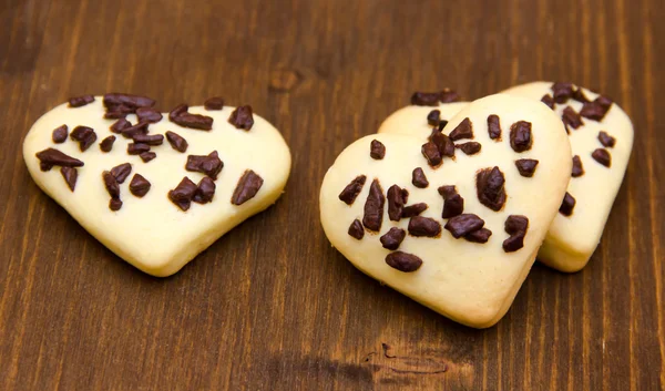 Biscoitos em forma de coração com chocolate em madeira — Fotografia de Stock