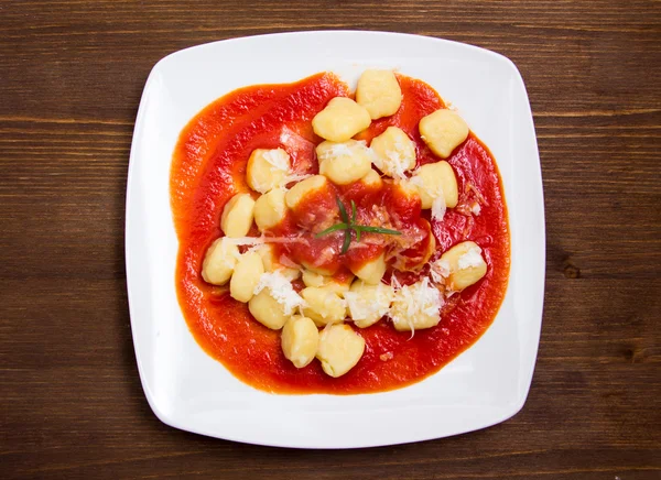 Gnocchi with tomato sauce on wood from above — Stock Photo, Image