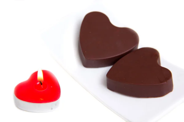 Vela y chocolates en forma de corazón cerca —  Fotos de Stock