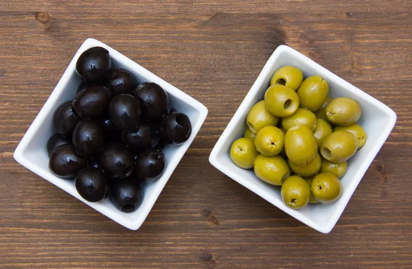 Bowls with green and black olives on wood from above — Stock Photo, Image