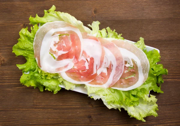 Rolled bacon on salad on wood from above — Stock Photo, Image