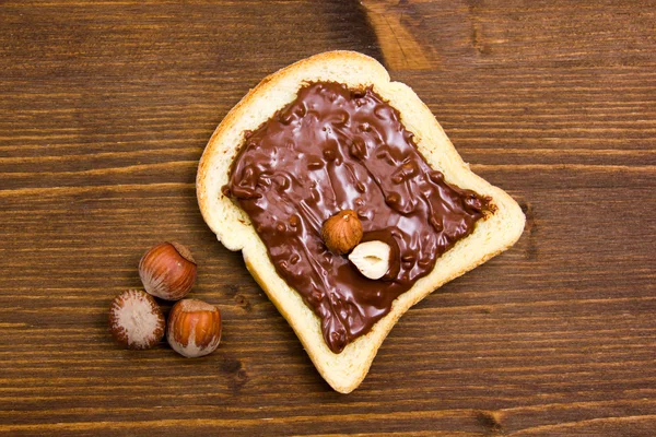 Rebanada de pan con chocolate con avellanas en madera de arriba — Foto de Stock