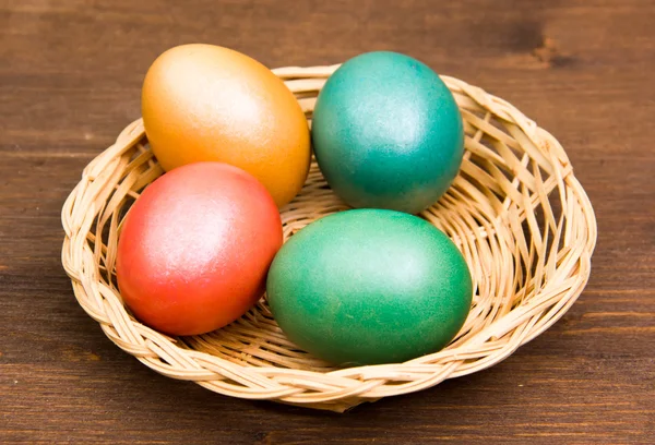 Koš s barevnými vejci na dřevo — Stock fotografie