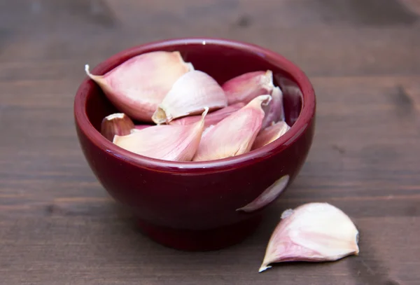 Cloves of garlic in bowl on wood — Stock Photo, Image