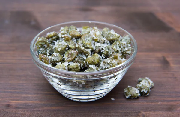 Salted capers in bowl on wood — Stock Photo, Image