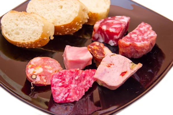 Trozos de salami y rebanadas de pan en el plato de cerca — Foto de Stock