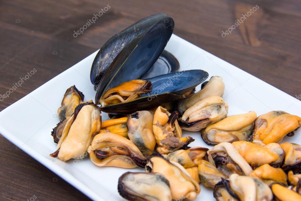 Mussels without shells on tray on wood close