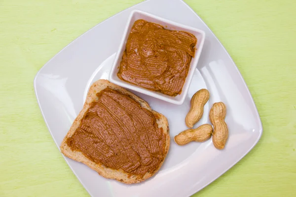 Fatia de pão com manteiga de amendoim no topo verde — Fotografia de Stock