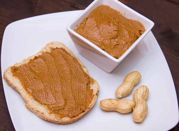 Rebanada de pan con mantequilla de maní en madera cerrar — Foto de Stock