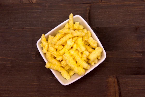 Snack de queso de maíz en cuenco cuadrado en madera de arriba — Foto de Stock