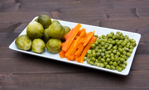 Tray with steamed vegetables on wood — Stock Photo, Image