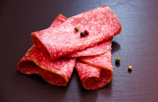 Slices of salami on slate — Stock Photo, Image