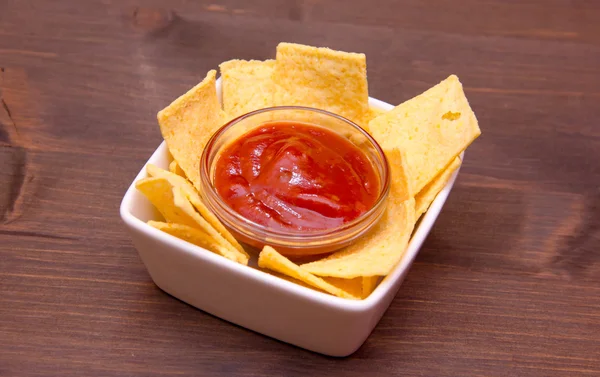 Cuenco con chips de maíz y salsa picante en madera — Foto de Stock