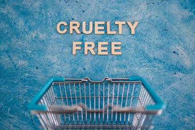 Vegan ürünleri ve hayvan hakları konsepti, Acımasızlık mavi arka planda alışveriş arabalı ücretsiz metin