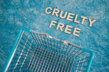 Vegan ürünleri ve hayvan hakları konsepti, Acımasızlık mavi arka planda alışveriş arabalı ücretsiz metin