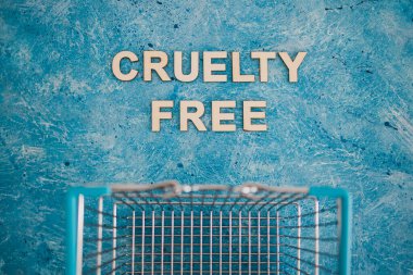 Vegan ürünleri ve hayvan hakları konsepti, Acımasızlık mavi arka planda alışveriş arabalı ücretsiz metin