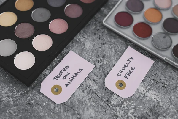cruelty free vs animal tested cosmetics concept, eyeshadow palettes with text on labels