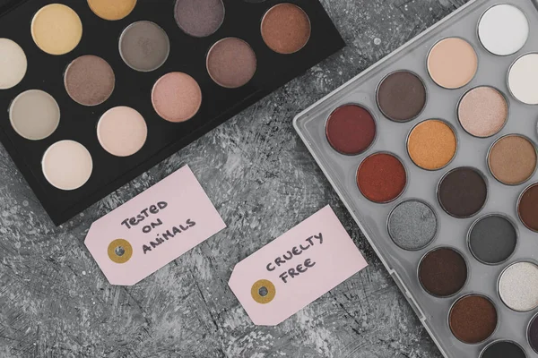 cruelty free vs animal tested cosmetics concept, eyeshadow palettes with text on labels