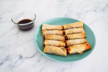 Sağlıklı bitkisel yemek tarifleri konsepti, soya sosunun yanında mavi tabakta kızartılmış sebzeli vegan ev yapımı börekler.