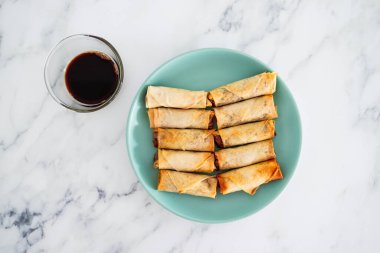 Sağlıklı bitkisel yemek tarifleri konsepti, soya sosunun yanında mavi tabakta kızartılmış sebzeli vegan ev yapımı börekler.