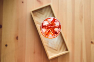 Tahta masanın üzerinde uzun bardakta portakal suyu kokteyli yakındaki pencereden parlayan altın ışık meyveli yaz içecekleri konsepti.