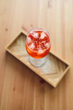 Tahta masanın üzerinde uzun bardakta portakal suyu kokteyli yakındaki pencereden parlayan altın ışık meyveli yaz içecekleri konsepti.