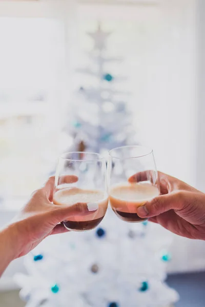couple cheering with espresso martinis with Christmas tree bokeh in the background shot at shallow depth of field