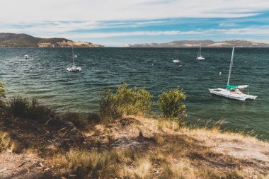 SNUG BEACH, AUSTRALIA - 26 Aralık 2020: Tazmanya, Avustralya 'da Güney Hobart' taki Snug Sahili 'nde el değmemiş vahşi doğa dalgalı mavi okyanusları ve yelkenli tekneleri ile