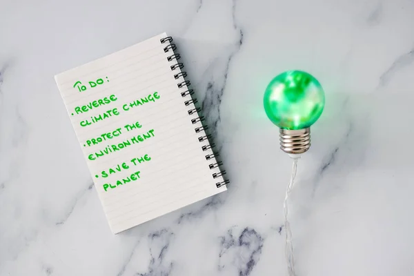 ecology and green ideas for the environment conceptual image, green light bulb next to to do list to save the planet