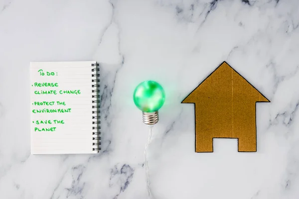 ecology and green ideas for the environment conceptual image, green light bulb next to to do list to save the planet and house icon