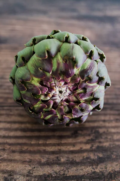 simple food ingredients concept, freshly harvested artichoke on wooden kitchen counter