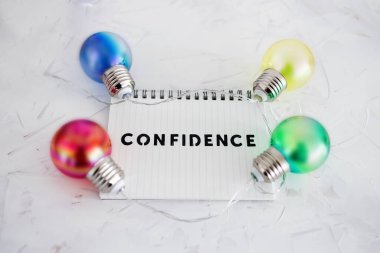 pozitif tutum konsepti, fikirlerin renkli ampulleriyle çevrili not defterine güven metni 